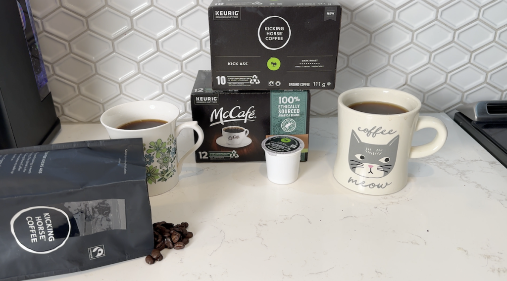 Two cups of coffee brewed using a K-cup and fresh ground beans placed on a counter.