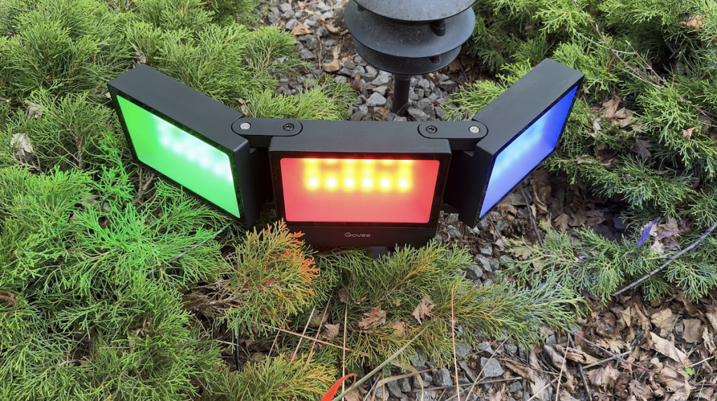 Govee Outdoor Triad Flood Lights in the ground lit up blue, red and green.