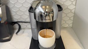 Nespresso Vertuo machine in white kitchen with espresso shot.