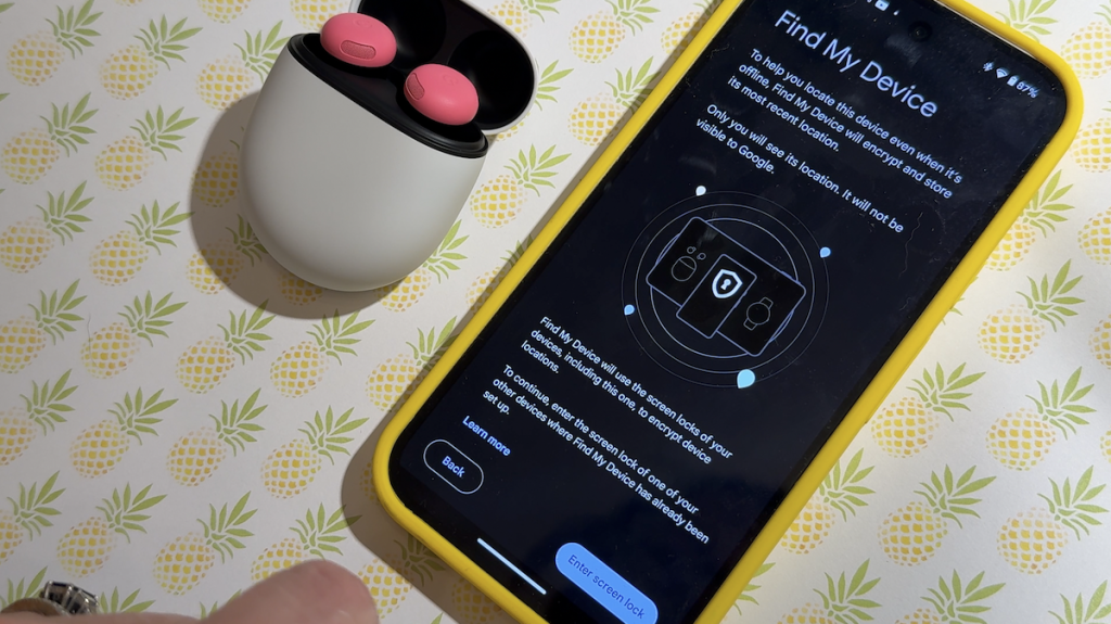 Pixel Buds Pro 2 in case on a table beside a smartphone.