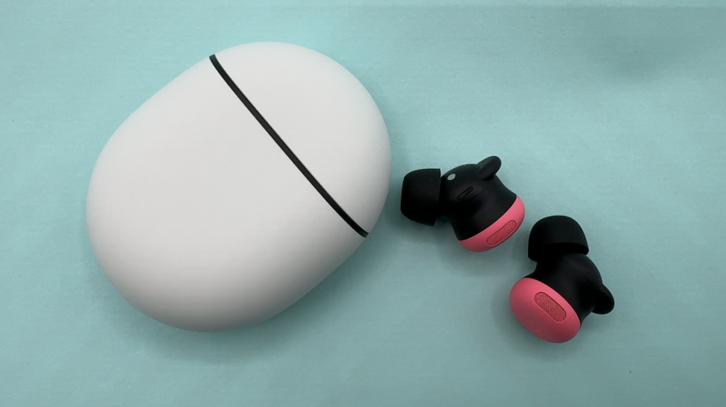 Pixel Buds Pro 2 laying beside closed case on table.