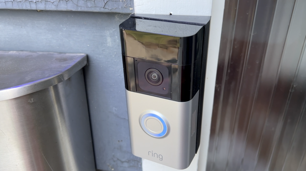 Ring video doorbell plus on blue siding near a door.